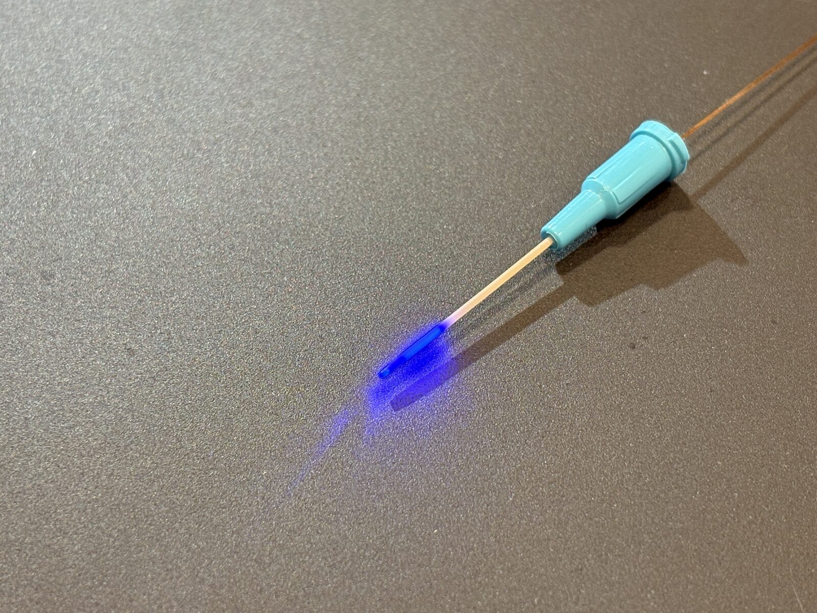 CD-2XS2 diffuser tip emitting 450 nm blue light at the end of a 22G cannula