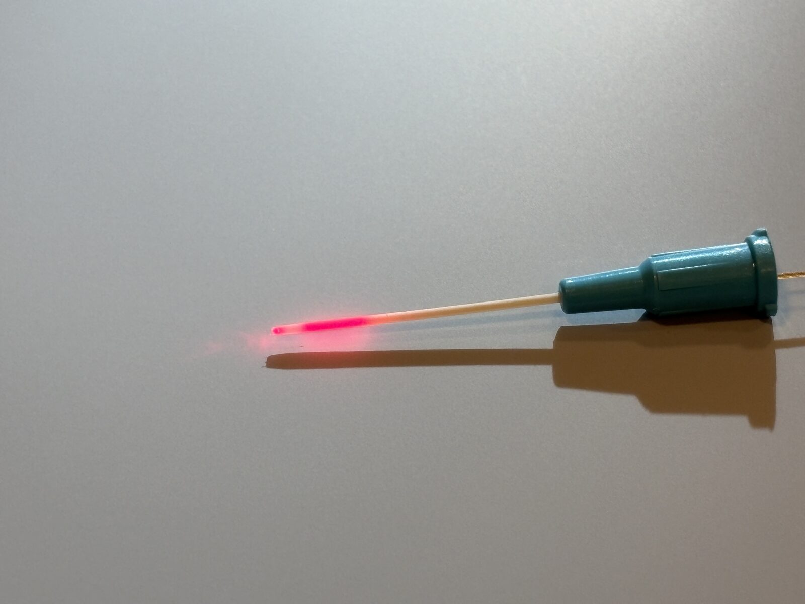 CD-2XS2 ultra-thin cylindrical diffuser emitting red light, emerging from a 22G cannula